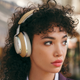 A model wearing the new Bowers & Wilkins PX8 wireless headphones in tan.